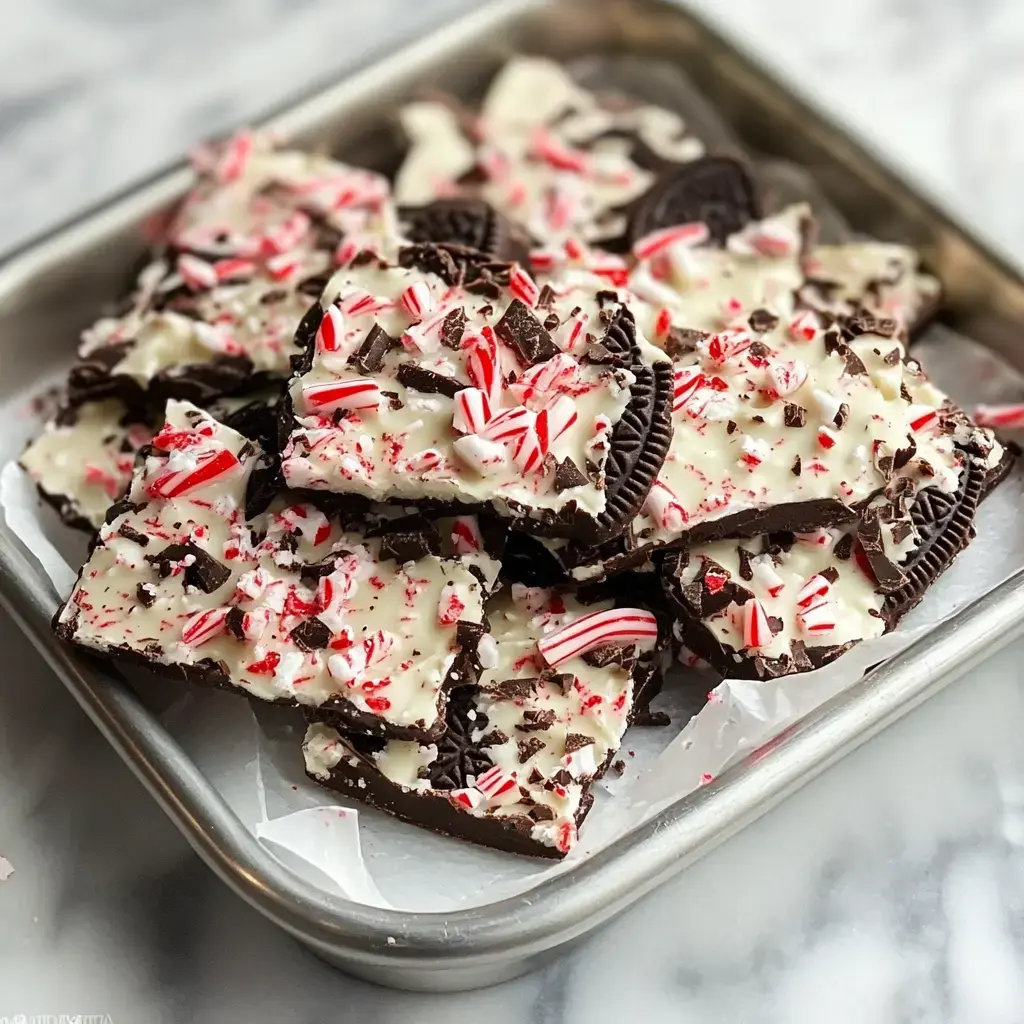 A tray of broken chocolate bark topped with crushed Oreos and crushed peppermint candies.