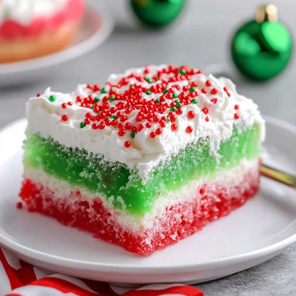 A vibrant dessert layered in red, green, and white with whipped cream and festive sprinkles on top.