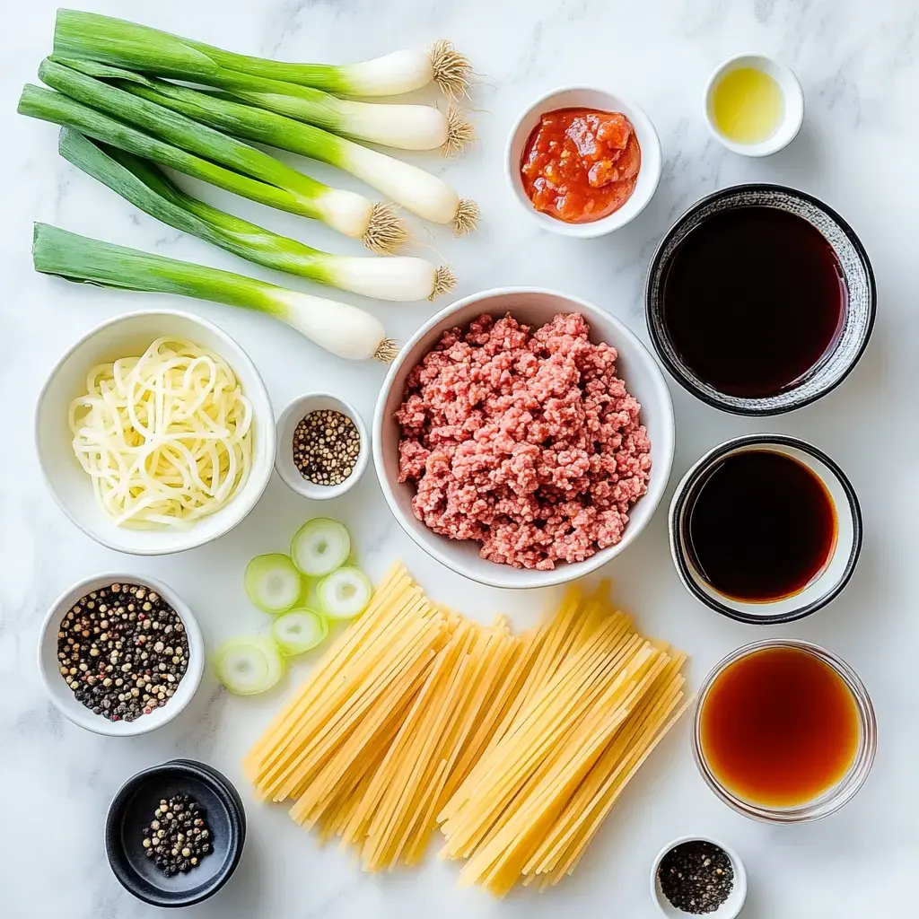 A variety of ingredients for cooking are displayed, including green onions, ground meat, noodles, sauces, and spices arranged on a marble surface.