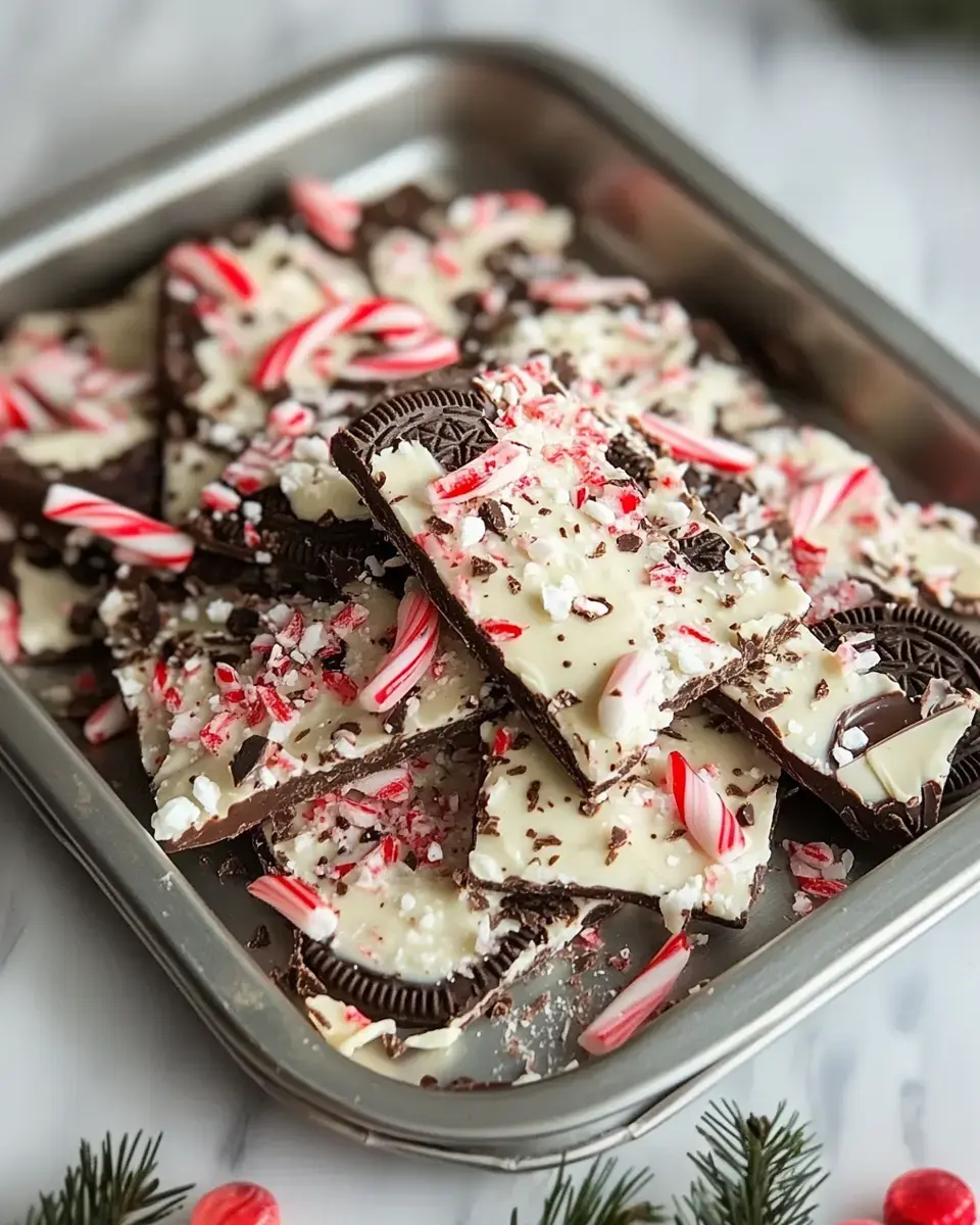 A silver tray filled with chocolate bark topped with crushed peppermint candies and Oreo pieces.