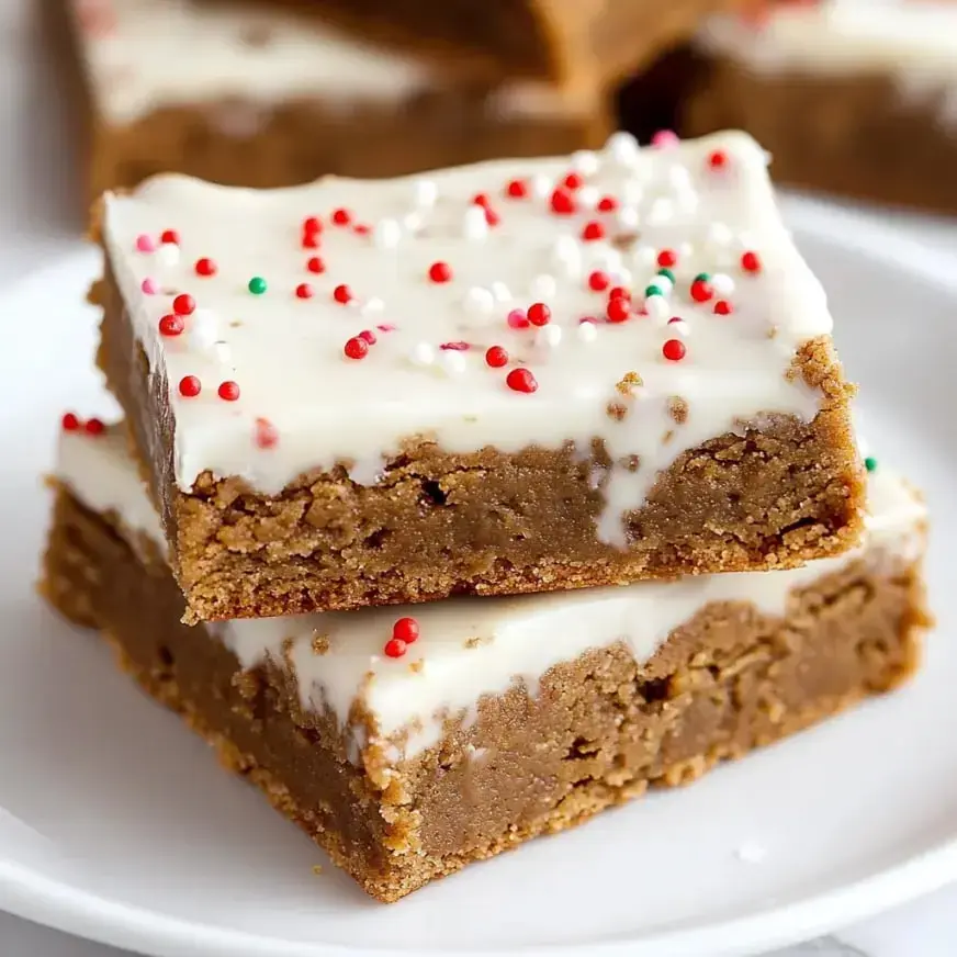 A close-up of two rectangular pieces of frosted dessert topped with colorful sprinkles on a white plate.