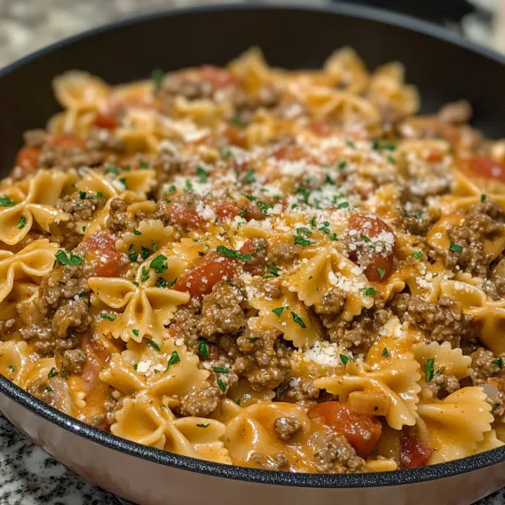 A bowl of pasta with meat and tomatoes.