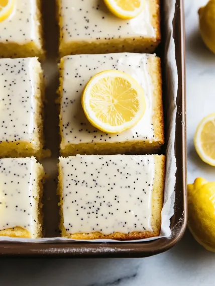 A square of lemon cake with lemon wedges on top.