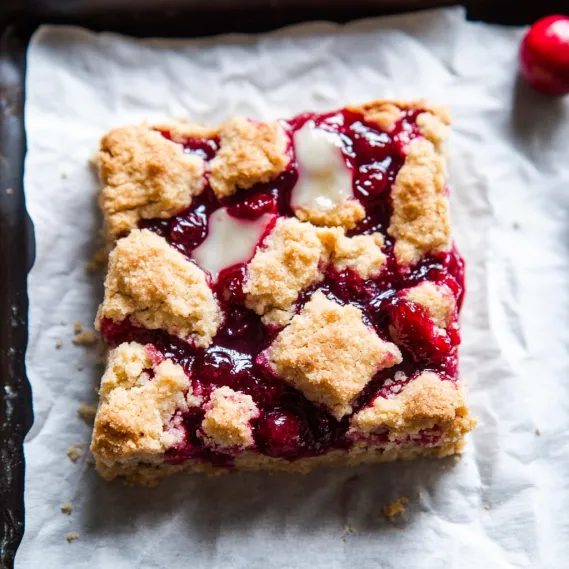 A square of cake with white frosting and red berries.