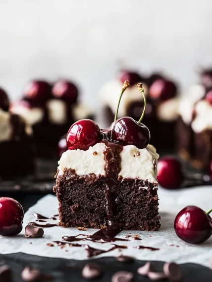 A slice of chocolate cake with cherries on top.