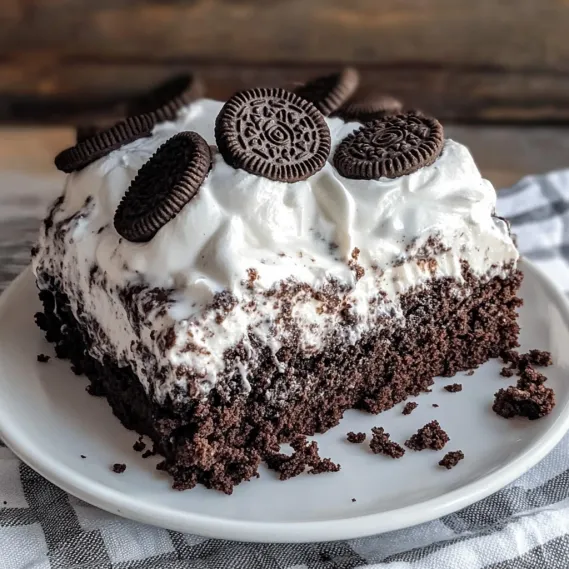 A slice of chocolate cake with white frosting and chocolate chips.