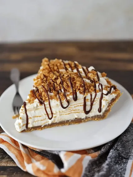 A slice of pie with chocolate drizzled on top.