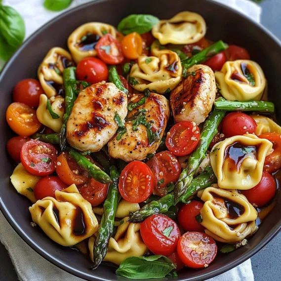 A bowl of food with tomatoes, chicken, and pasta.