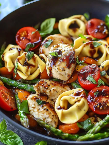 A bowl of food with tomatoes, chicken, and pasta.