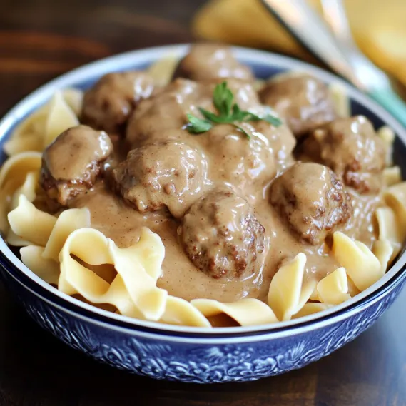 A bowl of pasta with meatballs and gravy.