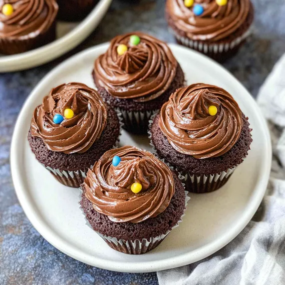A plate of cupcakes with chocolate frosting and yellow sprinkles.