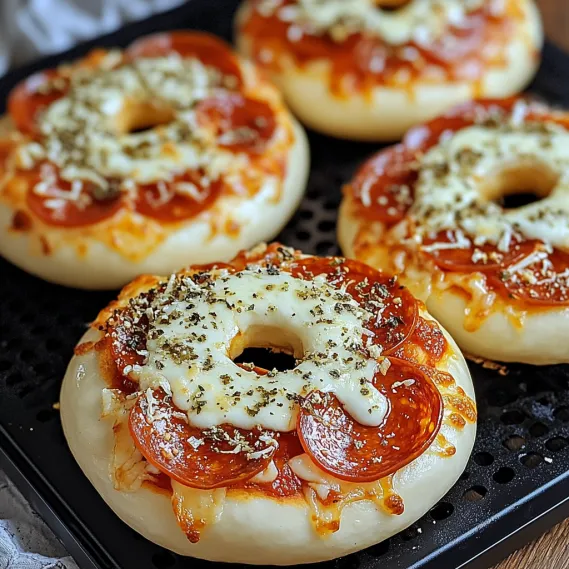 A pizza bagel with cheese and pepperoni on a black tray.