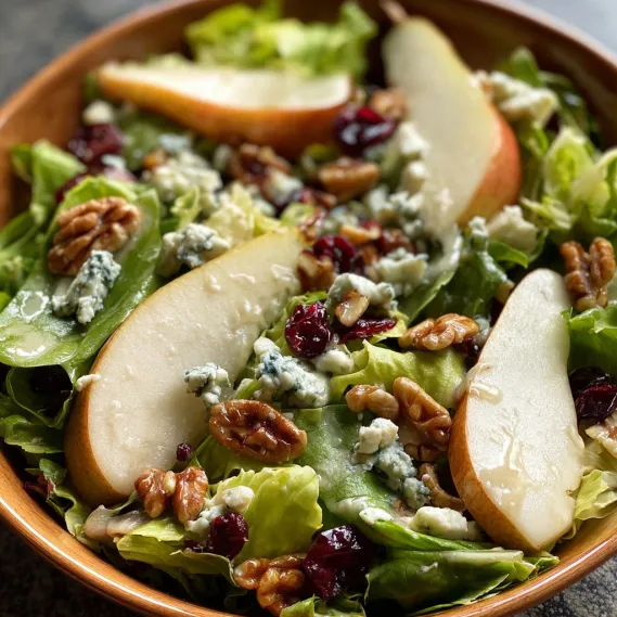 A bowl of salad with apples and walnuts.