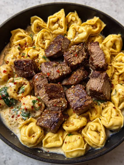 A bowl of pasta with meatballs and meat.