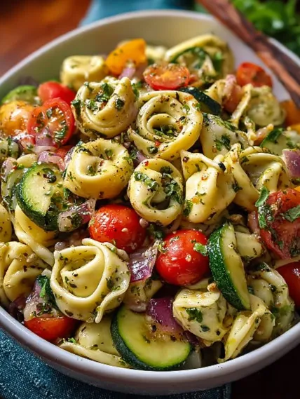 A bowl of pasta with tomatoes, zucchini, and basil.