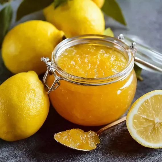 A jar of lemon jam with a spoon in it.
