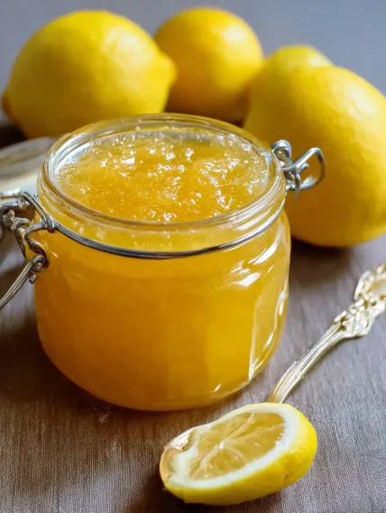 A jar of lemon juice with a lemon wedge on top.