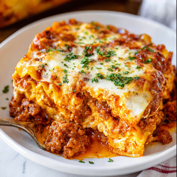 A white plate with a piece of lasagna on it.