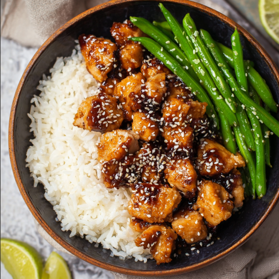 A bowl of rice and chicken with sesame seeds.