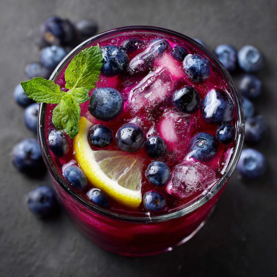 A glass of blueberry tea lemonade with a lemon wedge on the side.
