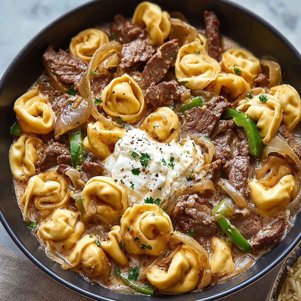 A bowl of cheesesteak tortellini provolone skillet.