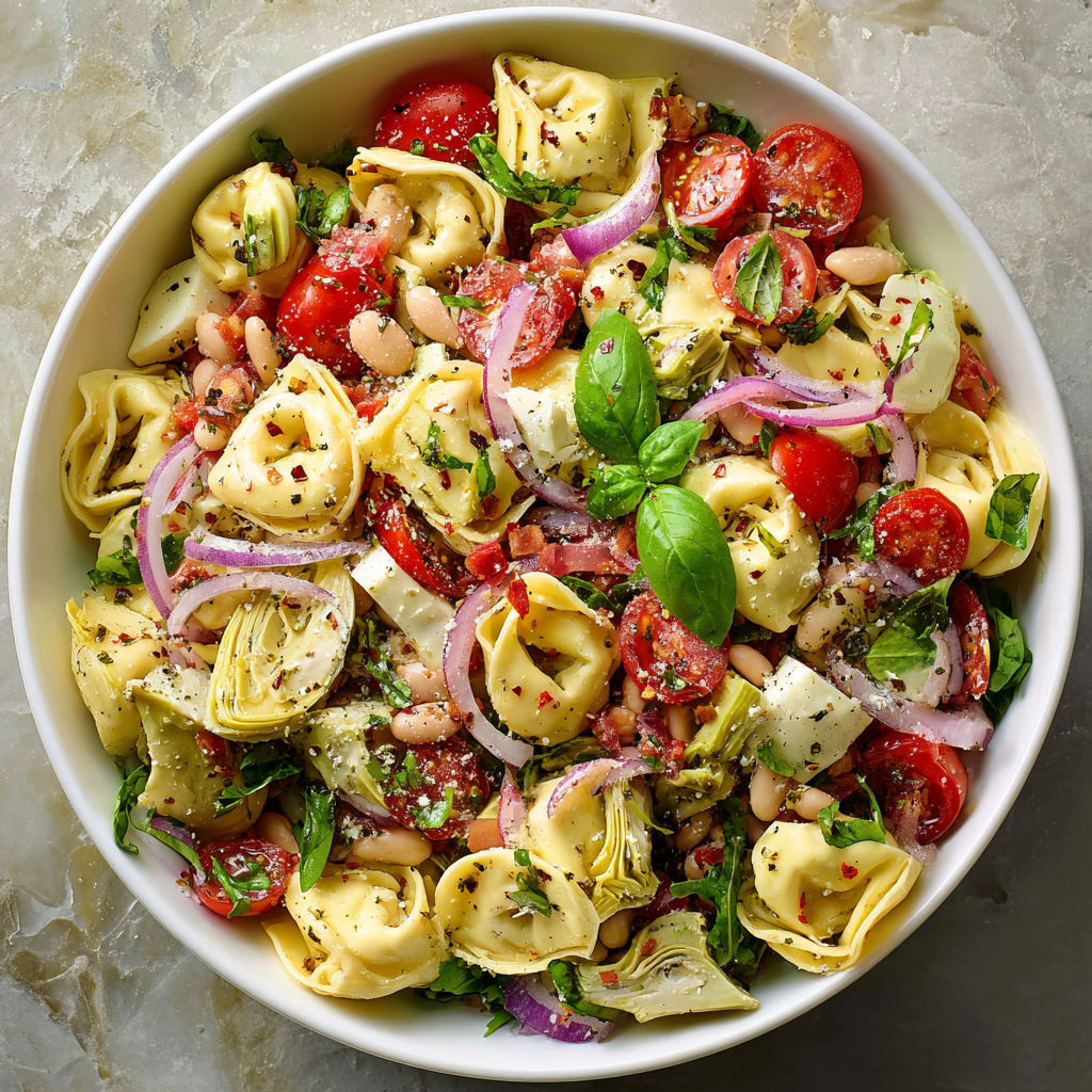 A bowl of pasta salad with tomatoes, beans, and spinach.