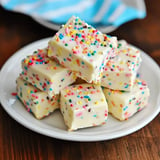 A plate of colorful, sprinkle-covered white chocolate fudge squares stacked on top of each other.