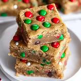 A stack of festive cookie bars adorned with red and green candies on top.