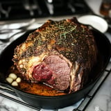 A perfectly cooked, seasoned roast resting in a cast-iron skillet with garlic and herbs.