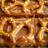 Close-up of a caramel-covered dessert topped with pretzel pieces.