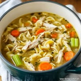 A bowl of chicken noodle soup with rotini pasta, shredded chicken, carrots, and celery in a savory broth.