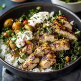 A bowl of food with rice, chicken, and vegetables.