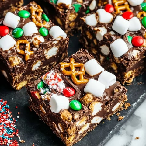 A close-up of delicious chocolate treats topped with colorful candies, marshmallows, and pretzels, arranged neatly on a dark surface.