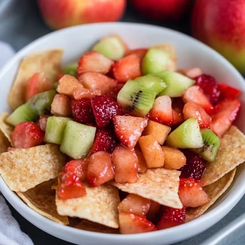 A bowl of fruit with a tortilla chip on top.