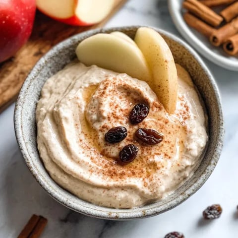A bowl of yogurt with raisins and cinnamon.