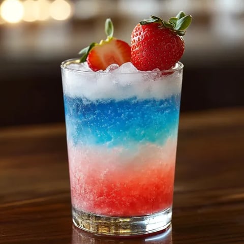 A glass of blue, red and white drink.