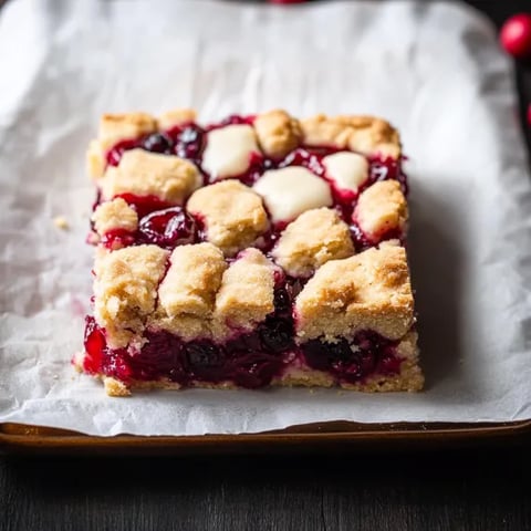 A square of cake with white frosting and berries.