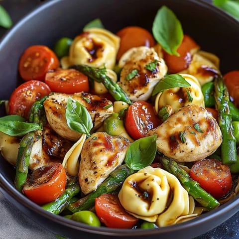 A bowl of food with tomatoes, asparagus, and chicken.