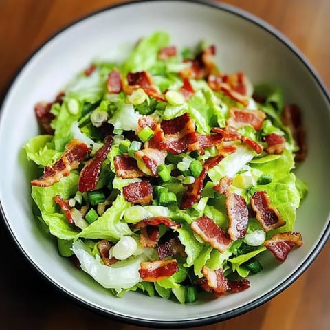A bowl of salad with bacon and lettuce.