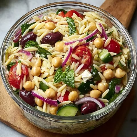 A bowl of food with tomatoes, cucumbers, and chickpeas.