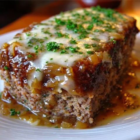 A slice of meat covered in cheese and herbs.