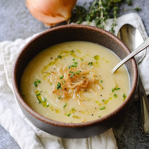 A bowl of soup with onions and potatoes.