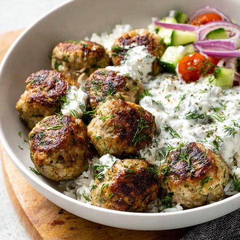 A bowl of Greek turkey meatballs with rice and a side of tzatziki.