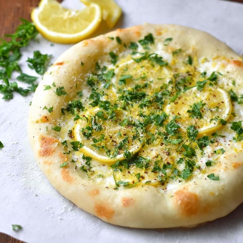 A pizza with lemon and herbs on top.