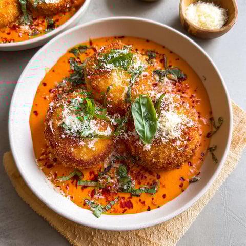 A plate of food with a red sauce and a bowl of cheese.
