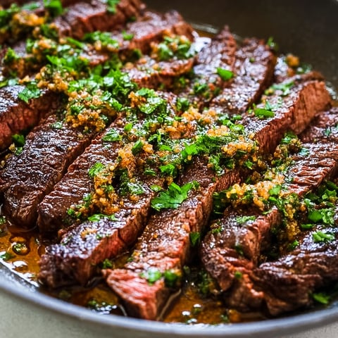 A plate of meat with garlic butter and herbs.