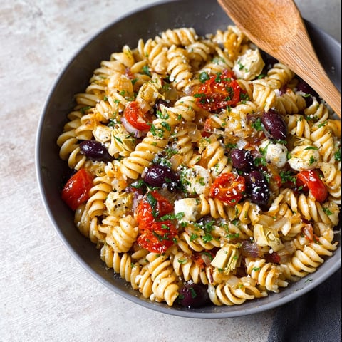A bowl of pasta with tomatoes, olives, and cheese.