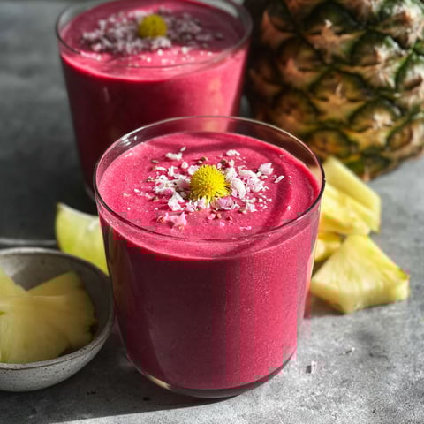 Two glasses of a pink smoothie with pineapple and beets.