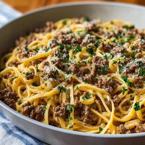 A bowl of pasta with ground beef and garlic butter.
