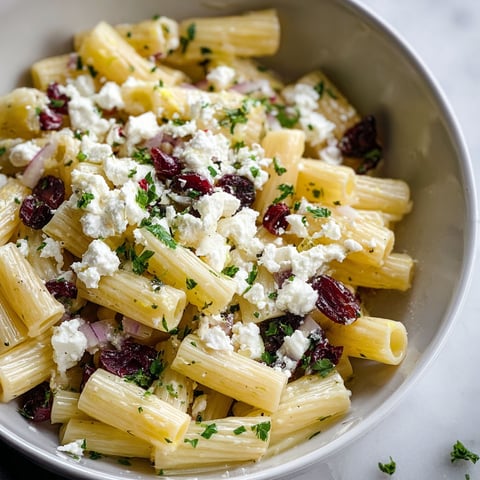 A bowl of pasta with feta cheese and cranberries.